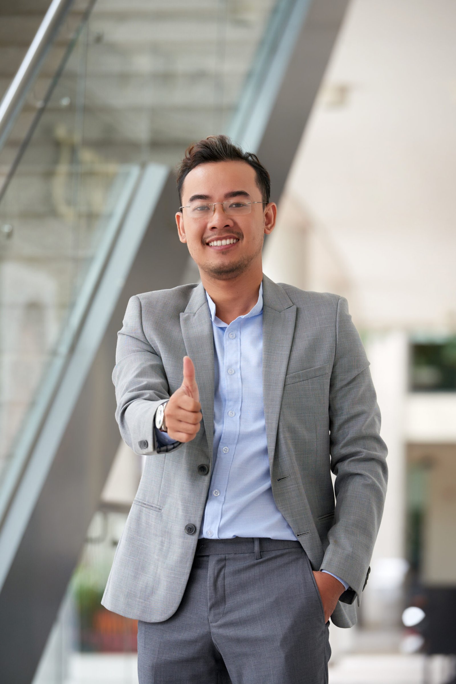 Portrait of cheerful Asian businessman showing thumbs-up